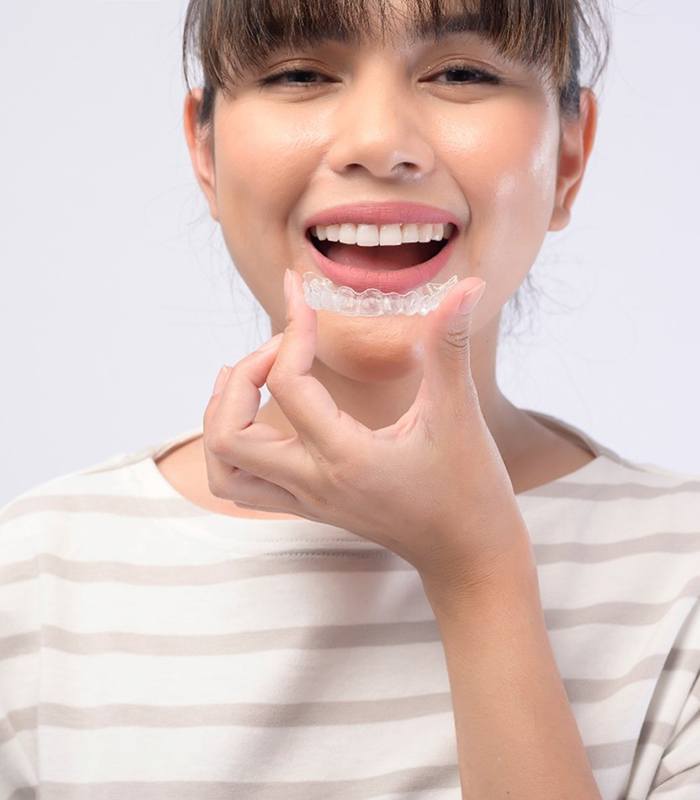 Smiling woman about to put in a SureSmile aligner