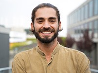 a smiling man with a tan shirt on