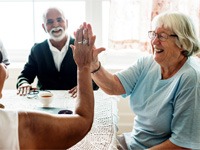 mature people smiling with dental implants and giving high fives