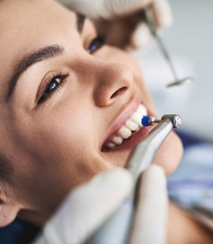 Female dental patient receiving dental cleaning with electric brush