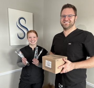 Dental team holding box and toothbrushes