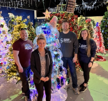 Dental team standing next to Christmas trees