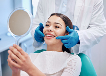 Dentist showing patient smile in a handheld mirror