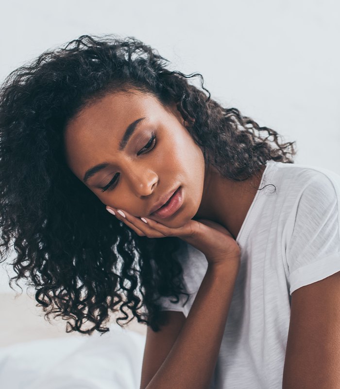 Woman in need of emergency dentistry holding cheek in pain