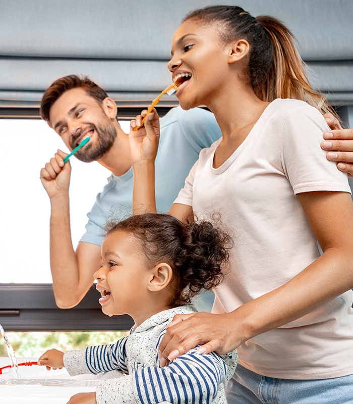 Family brushing teeth together to prevent dental emergencies