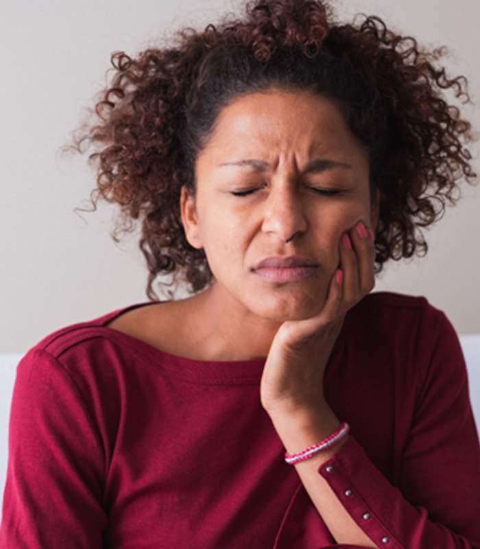 Woman with toothache sitting on couch at home