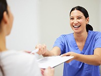 a front desk team member handing a patient a form