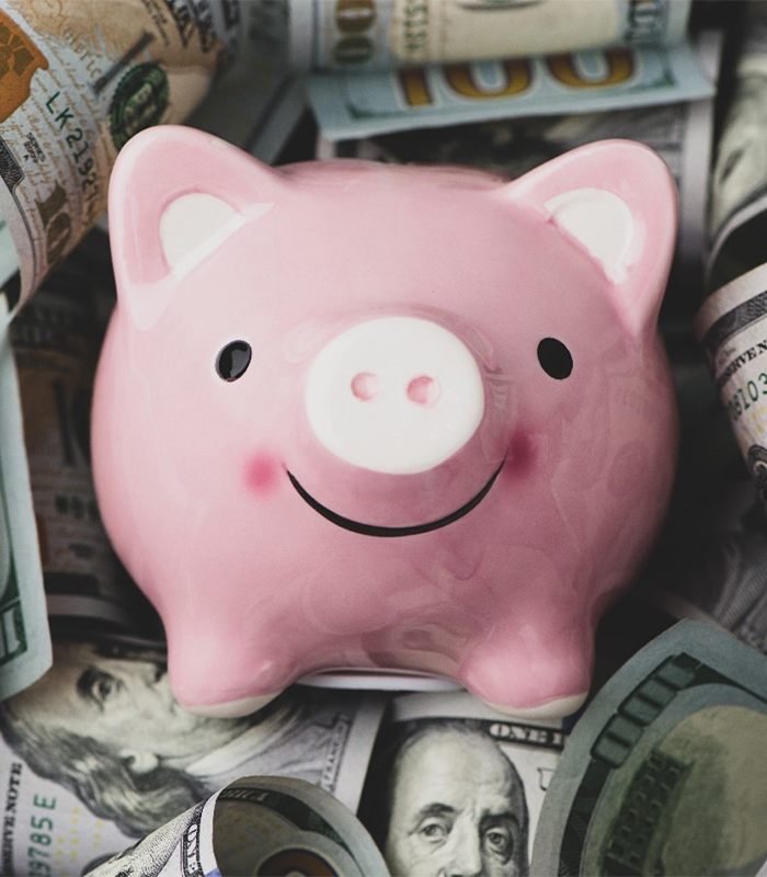 Piggy bank on dollar bills for dental implants in Jonesboro