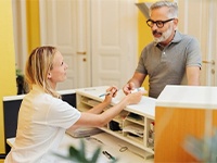 Man paying at front desk for dental implants in Jonesboro