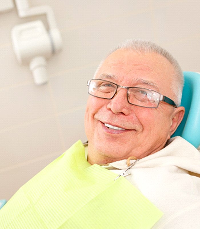 Happy senior man at appointment for implant dentures