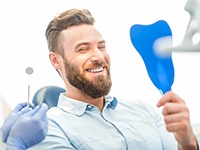 man admiring his new teeth in a mirror 