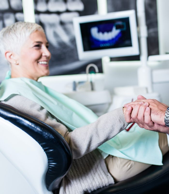 Smiling woman in dental chair discussing dental implant tooth replacement