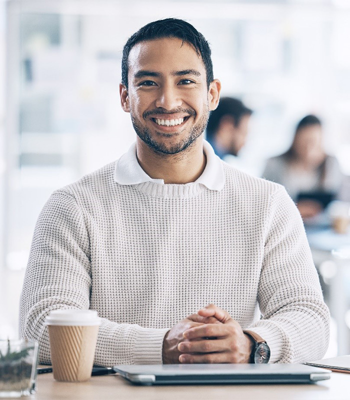 a person smiling and sitting at a desk