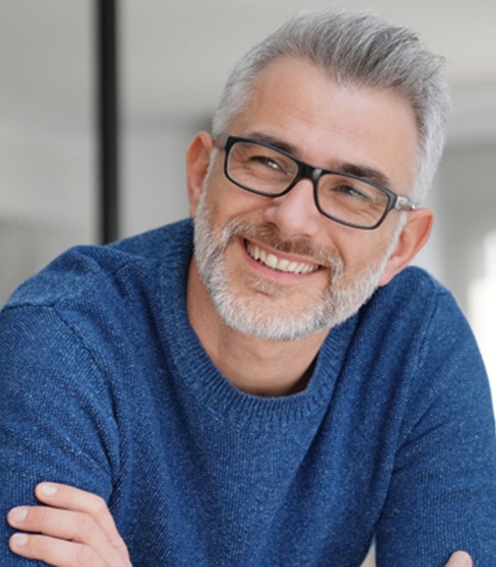 Man with blue shirt and glasses sitting and smiling