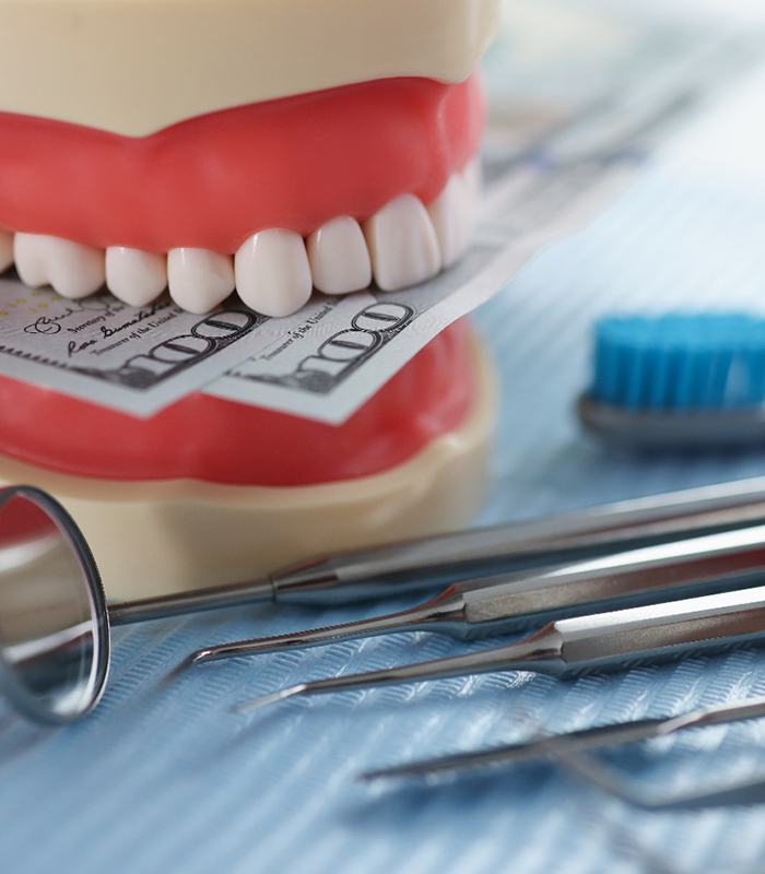 An artificial jaw mockup with money, an image that symbolizes the cost of a root canal in Jonesboro 