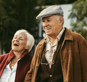 Older couple laughing together after replacing missing teeth