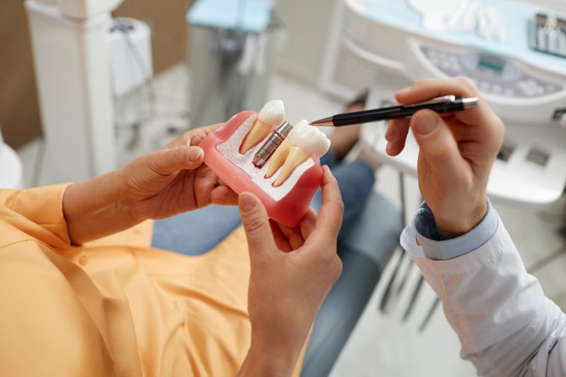 A senior woman holding a tooth model during consultation on dental implant surgery