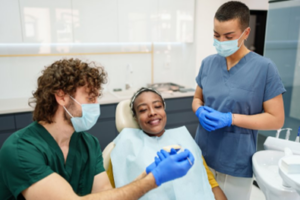 Two dentists explaining to patient how to properly use denture adhesive