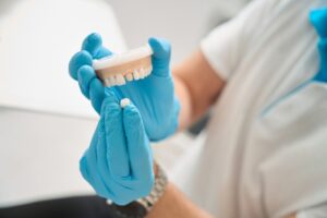Dentist holding model of dental crown. 