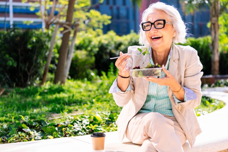 Lady smiles while eating salad