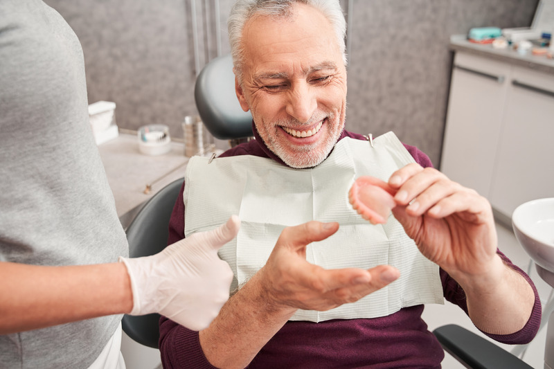 Older patient smiling at their new set of dentures